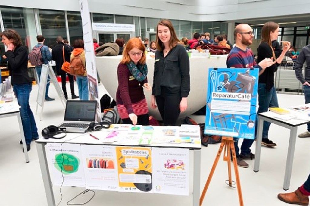 Zwei Frauen stehen an Messestand und schauen Infomaterial an