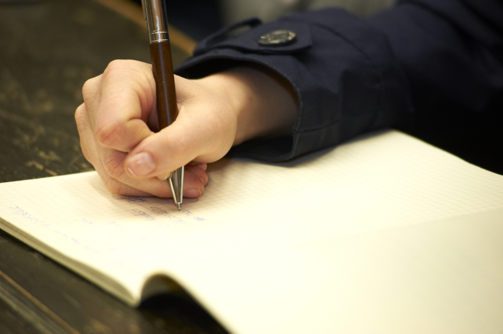 Hand schreibt mit Stift in Buch