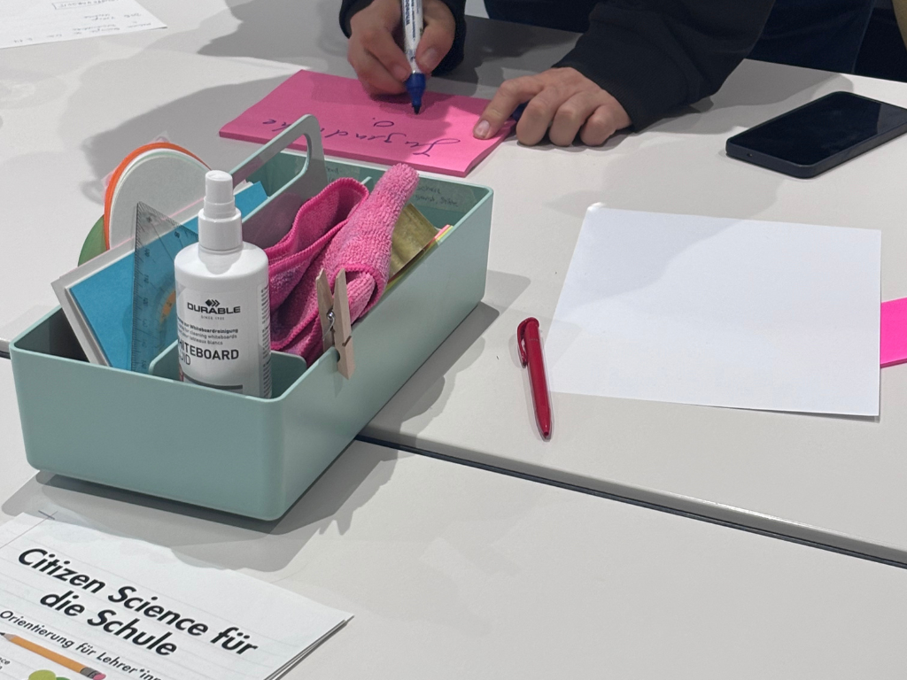 Gruppenarbeit Teilnehmender schreibt etwas auf einen Post-it