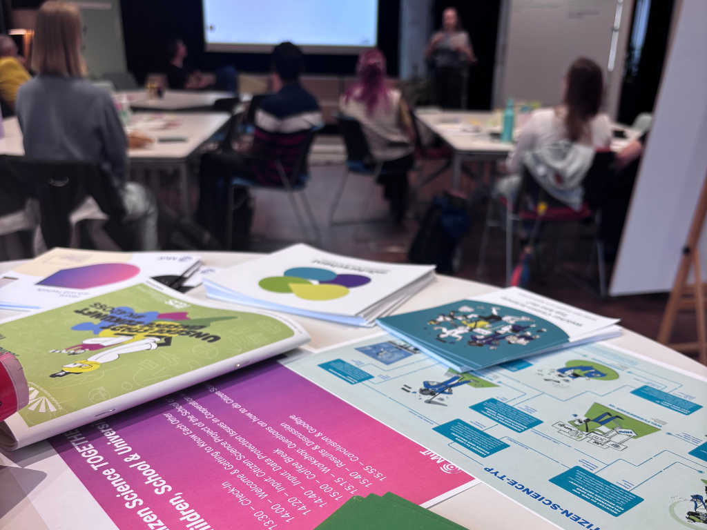 Flyers zu verschiendenen Programmen mit Citizen Science, im Hintergrund Vortrag von Hannah Wahler