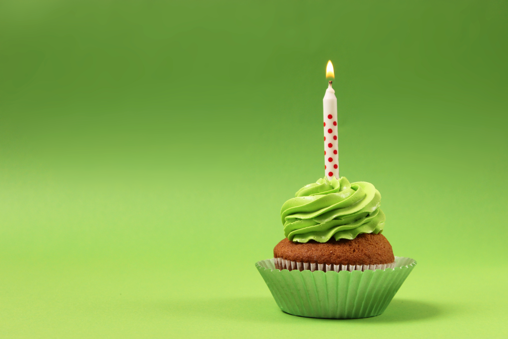 Delicious cupcake with a candle on a colored background 