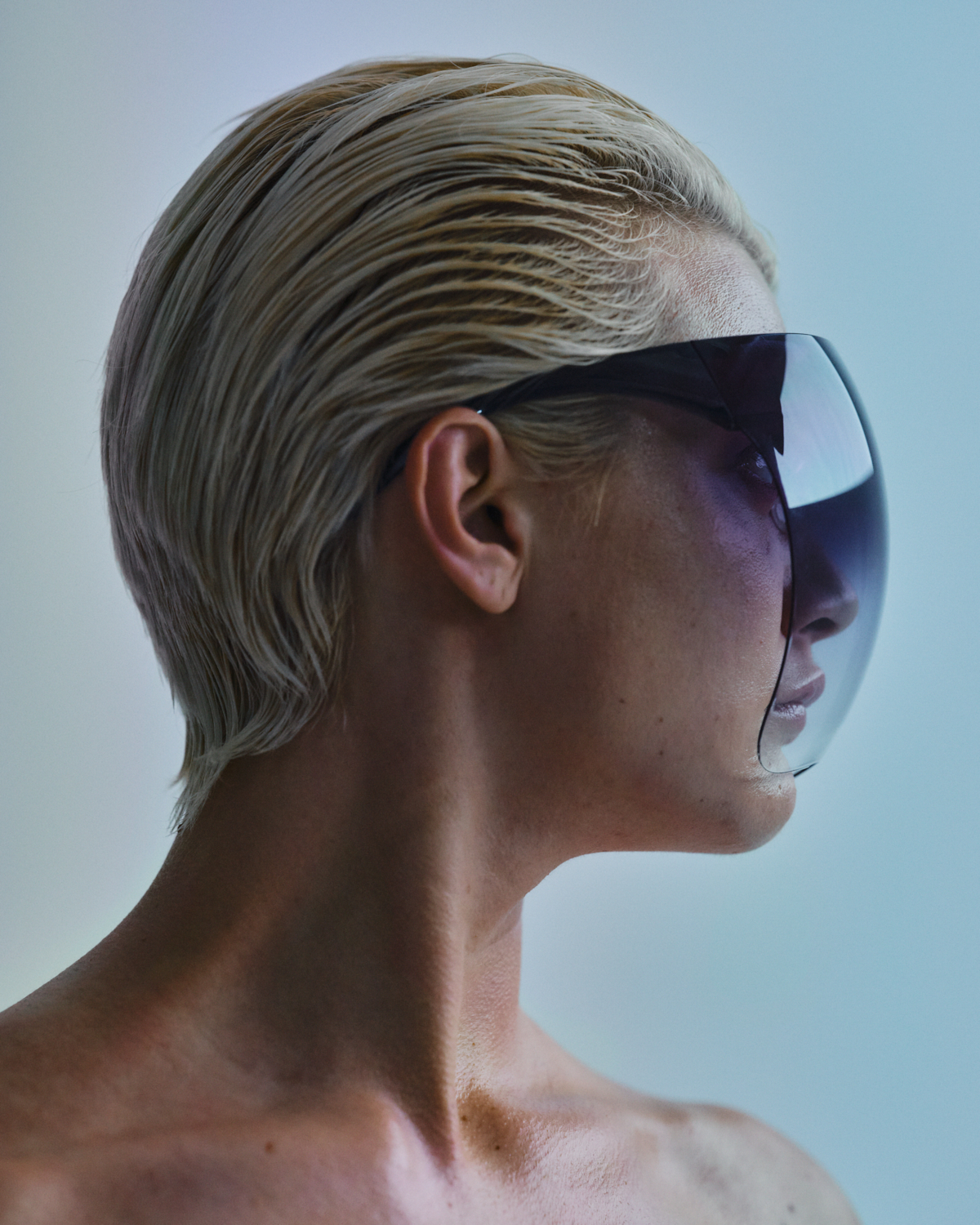 Frau mit zurückgekämmten Haaren trägt transparenten, futuristischen Helm.